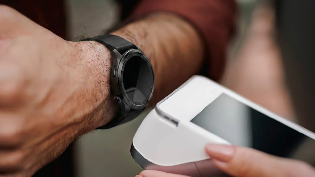 Handgelenk mit Uhr am Bezahlarmband wird an ein Kartenterminal gehalten